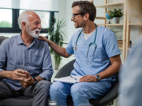 Blije dokter aan het praten met een oude man