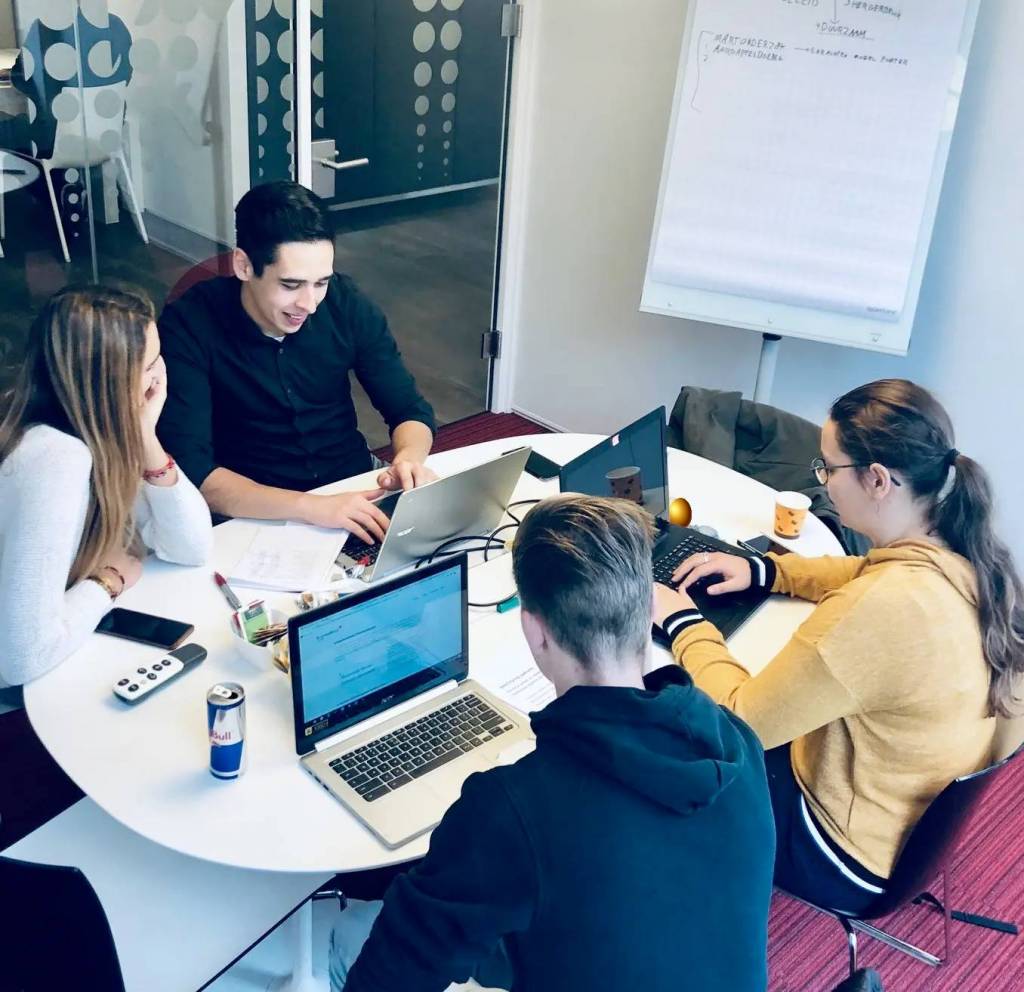 Mensen achter laptops aan het overleggen aan een tafel