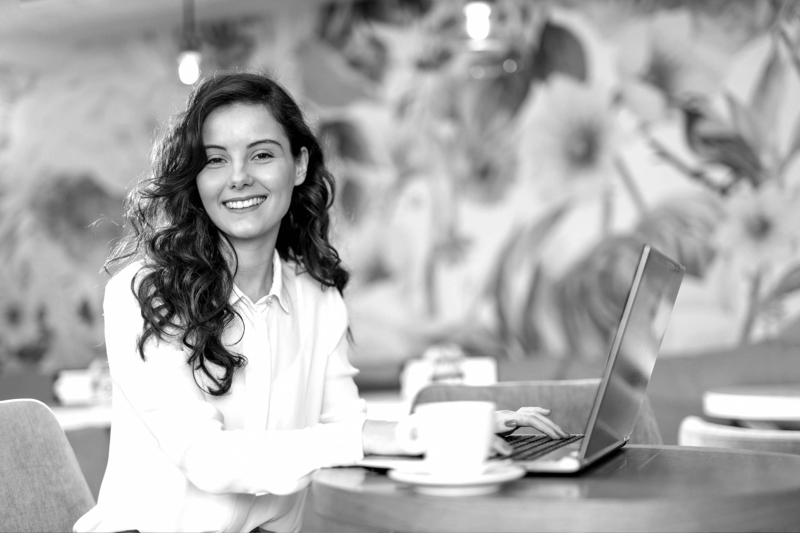 Vrolijke vrouw achter een laptop met een kop koffie