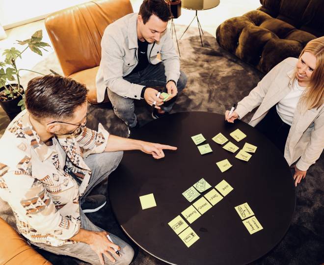 3 mensen brainstormen aan een ronde tafel